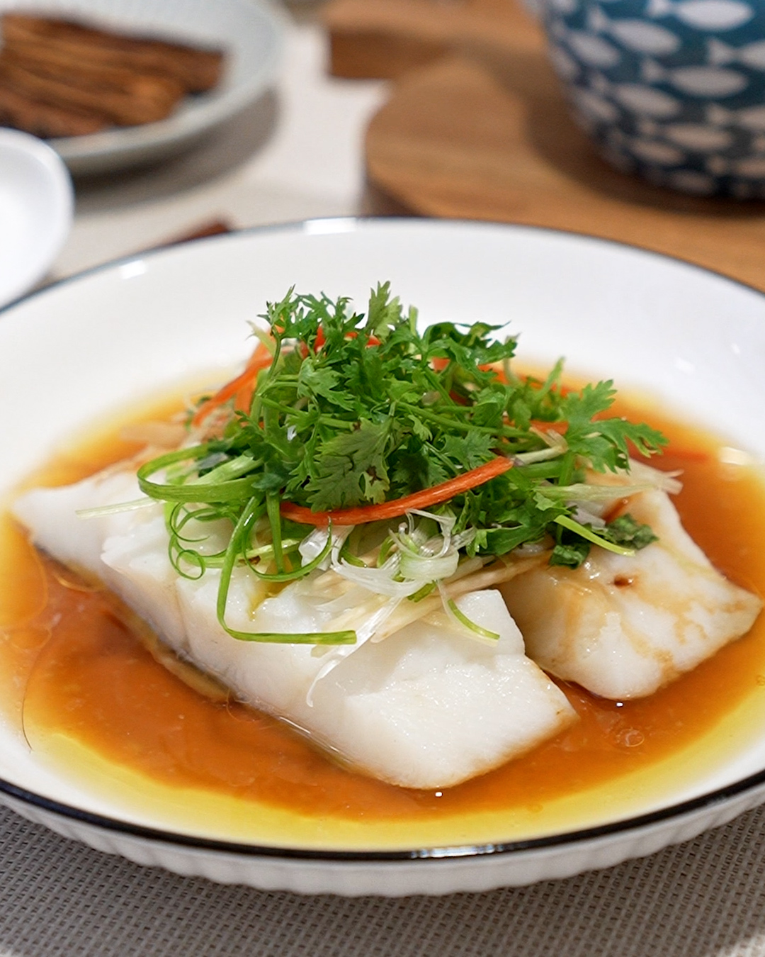 Steamed fish with fragrant oil and herbs topped with ginger and spring onions