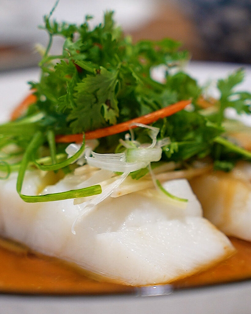 close-up of tender steamed fish with fragrant oil and herbs
