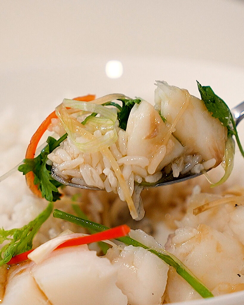 scooping up some steamed fish with fragrant oil and herbs and rice with a spoon