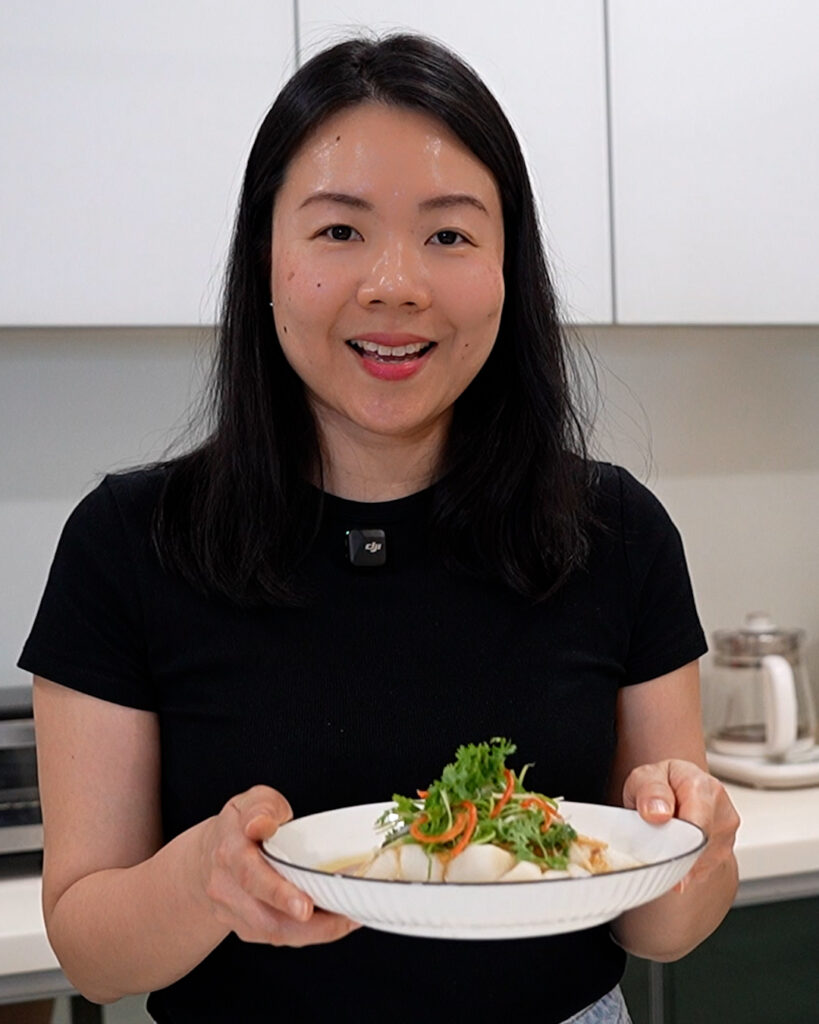 serving steamed fish with fragrant oil and herbs with chopsticks