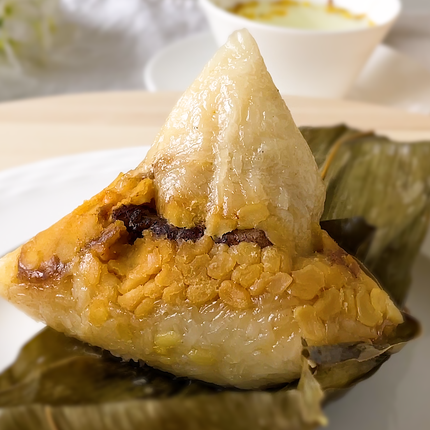 Close-up of white Hokkien bak chang cut open showing glutinous rice with savoury pork belly, mushroom and chestnut filling