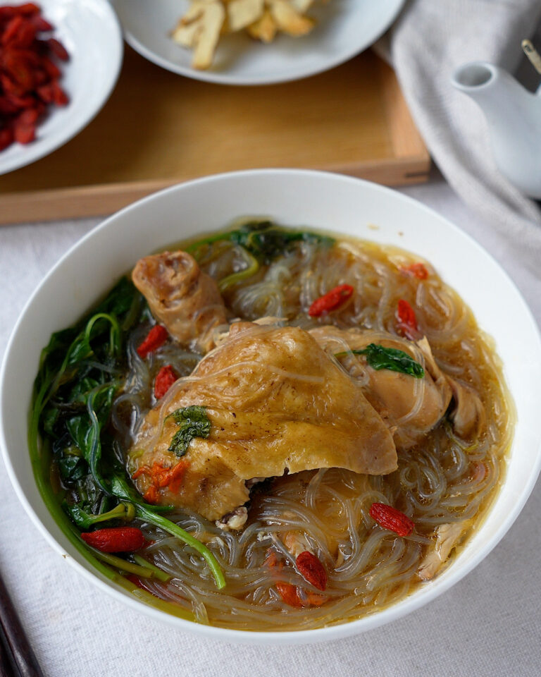 One pot herbal chicken with noodles cooked in a rice cooker, served in a bowl with glass noodles, vegetables and clear herbal broth