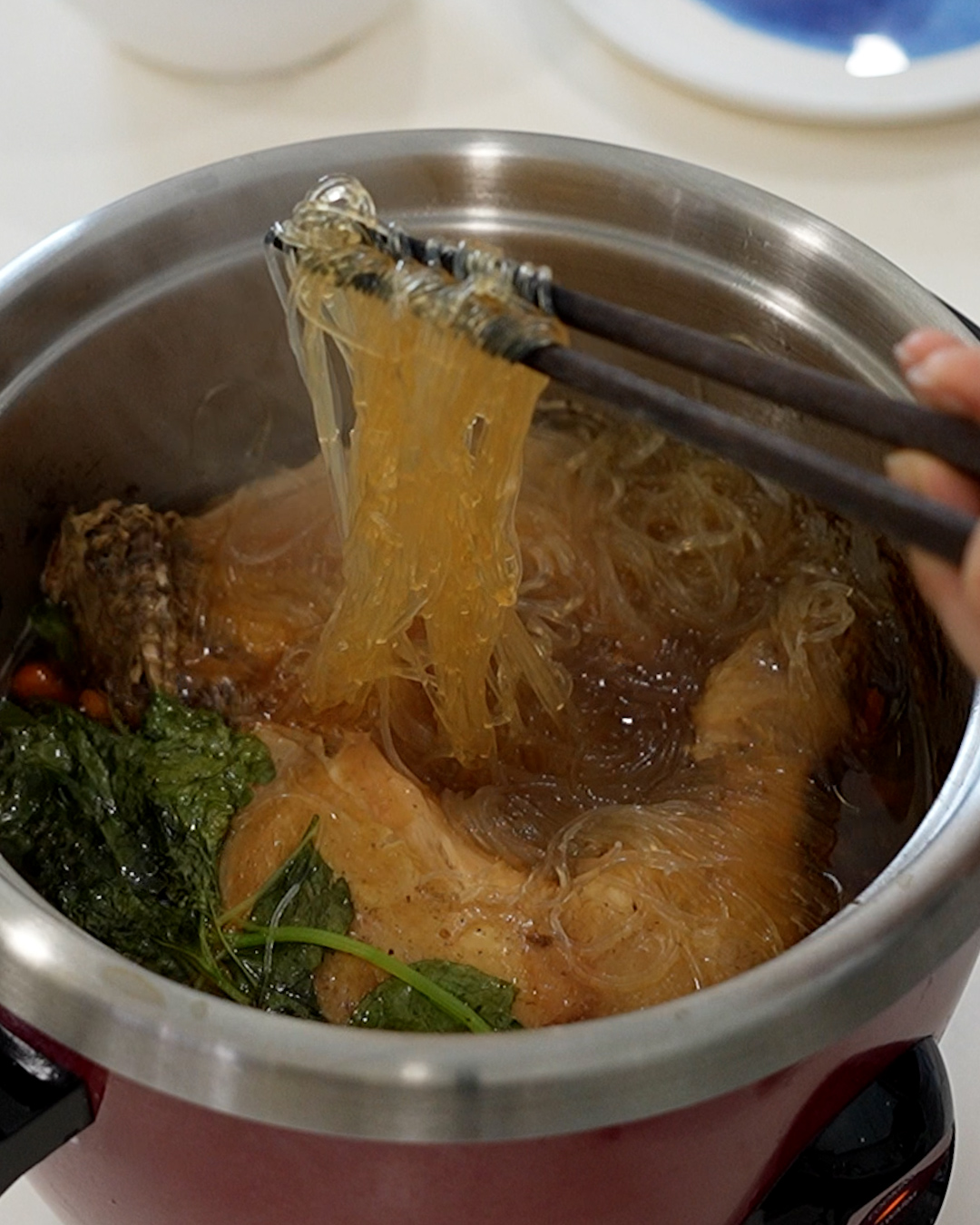 Close-up of one pot herbal chicken noodle soup with soft chicken meat falling off the bone and glass noodles in herbal broth