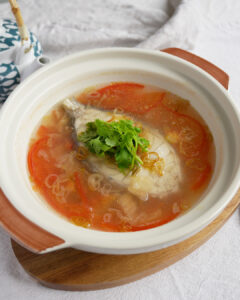 Simple fish soup with tomato and Tianjin preserved vegetables in a ceramic bowl, garnished with crispy shallots and fresh coriander