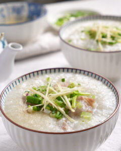 Easy pork ribs porridge cooked in a rice cooker, served in a bowl with julienned ginger and spring onions
