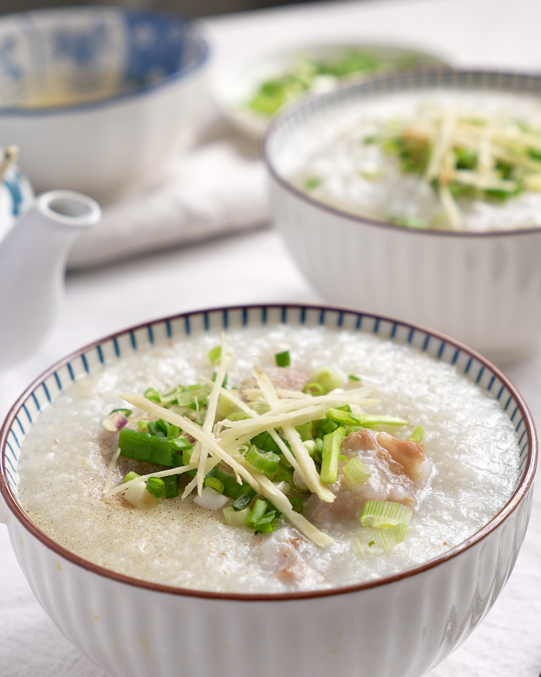 Easy pork ribs porridge cooked in a rice cooker, served in a bowl with julienned ginger and spring onions