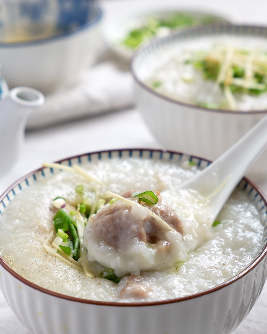 A bowl of homemade Chinese pork ribs porridge garnished with ginger strips and diced spring onions
