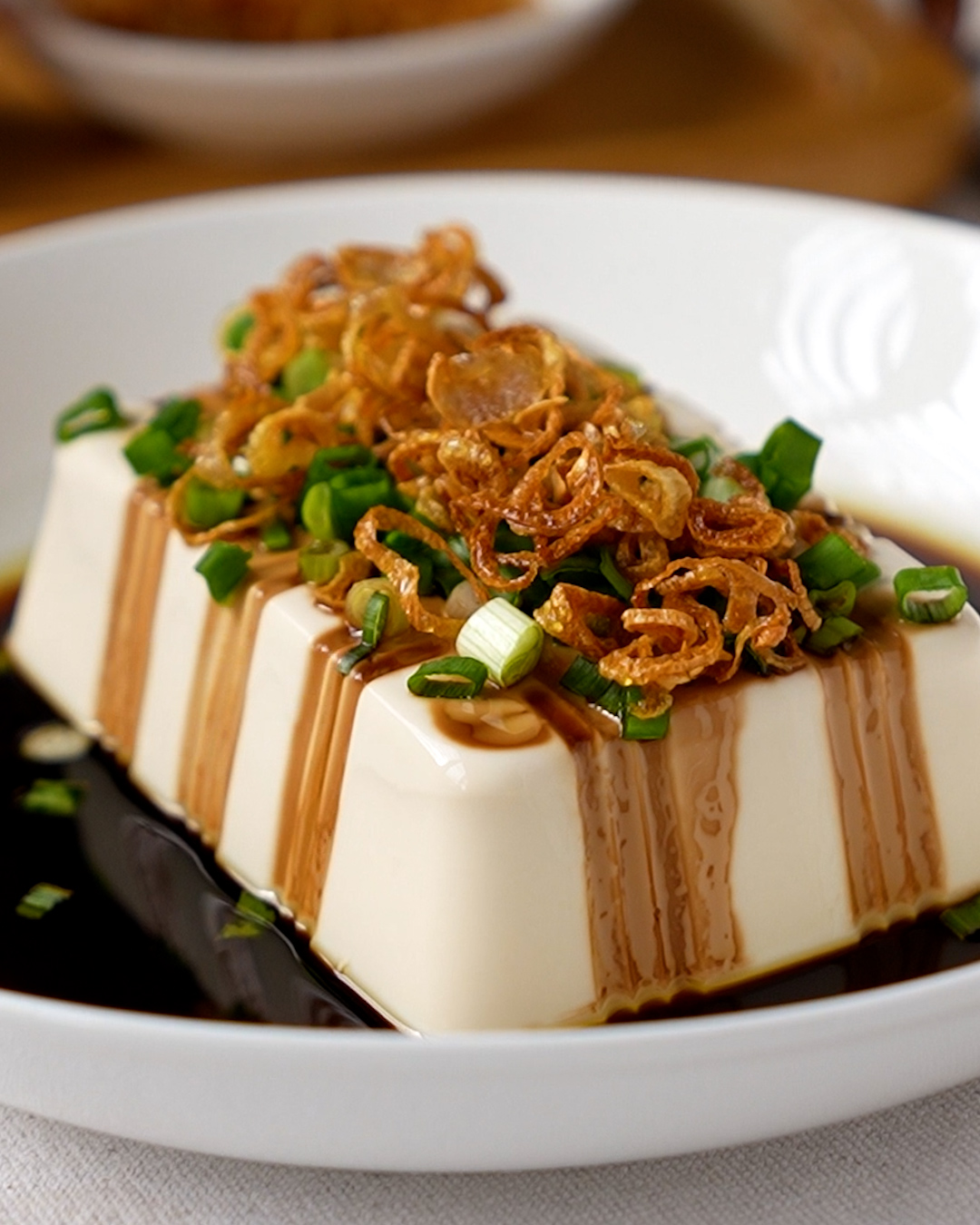 Close-up of silken tofu with shallot oil sauce, light soy sauce and crispy shallots on top