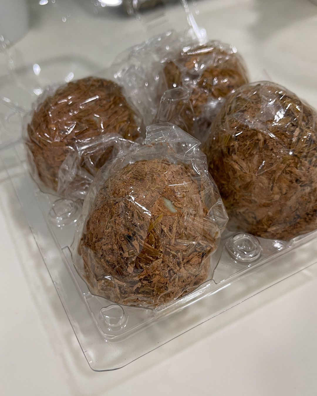 Whole century eggs still wrapped in their traditional rice hull and clay coating