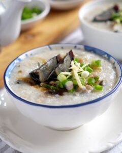 Minced pork century egg porridge in a rice cooker, garnished with spring onion and ginger