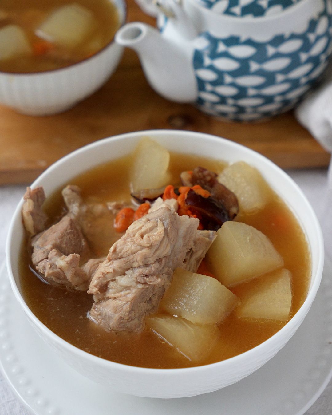 Pork ribs soup with winter melon served in a bowl, garnished with goji berries and red dates