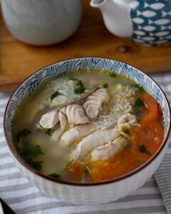 Sour plum fish soup with leftover rice served in a blue and white bowl