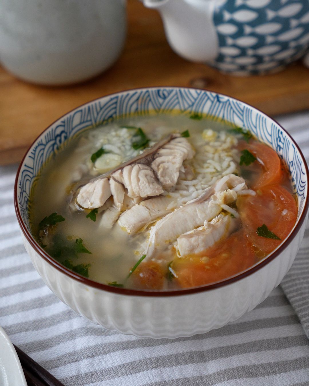Sour plum fish soup with leftover rice simmering in a claypot with a spoon