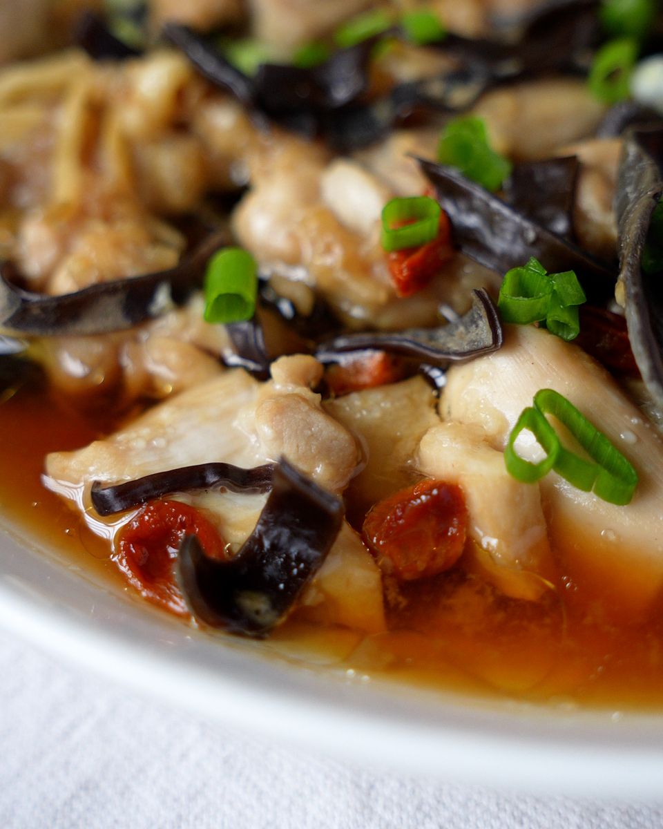 Steamed chicken with black fungus and goji berries garnished with chopped spring onion