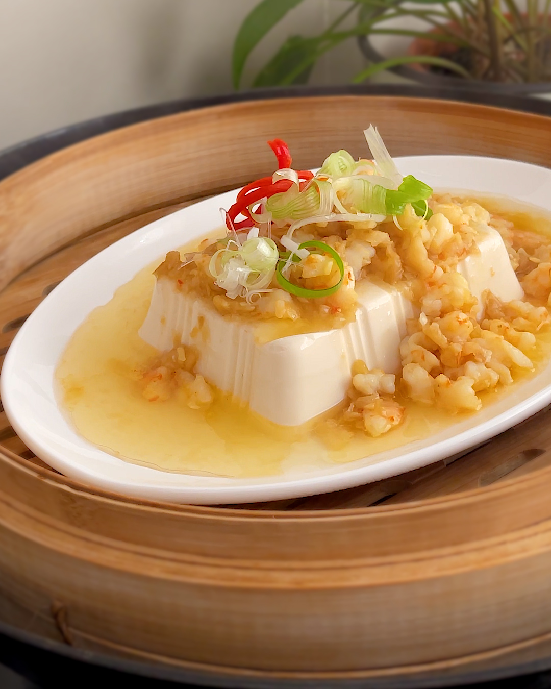 Steamed tofu with preserved radish and prawns served in a bamboo steamer basket