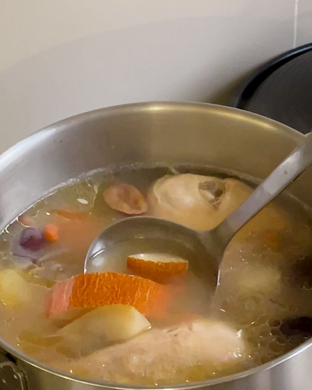 Close-up of old cucumber soup with chicken showing old cucumber chunks, red dates and goji berries in a clear broth