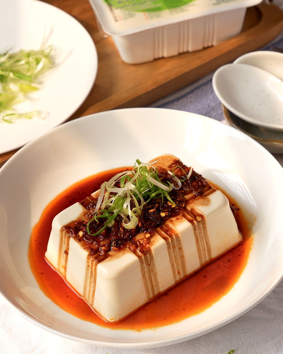 Cold silken tofu recipe served in a white bowl with chili oil and soy sauce pooling around it