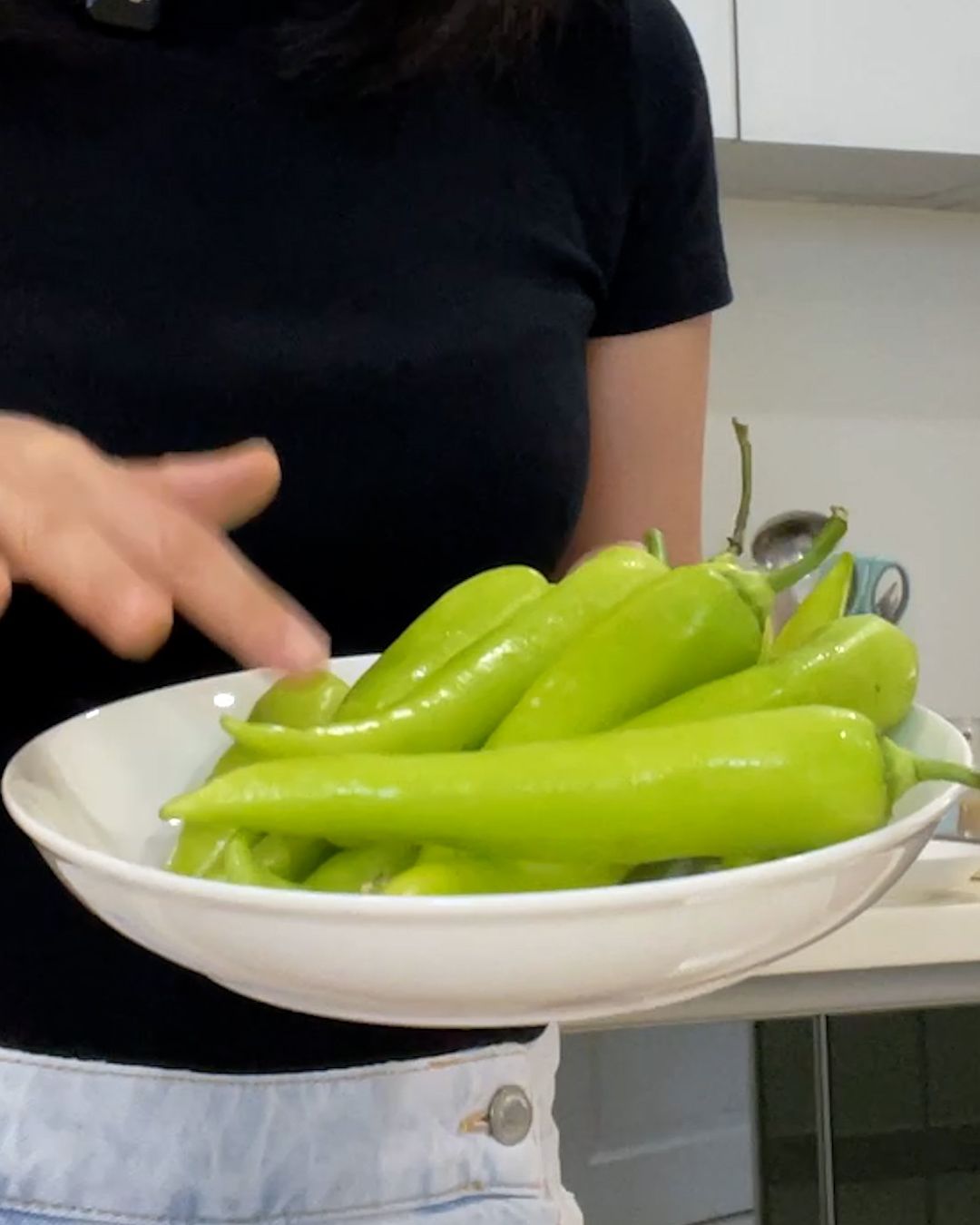 Plate of whole raw Charleston green chili peppers, long and tapered with a glossy bright green skin