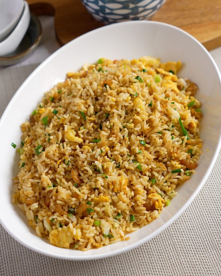 Chinese egg fried rice with dried shrimp, scrambled egg and spring onions in a white serving dish