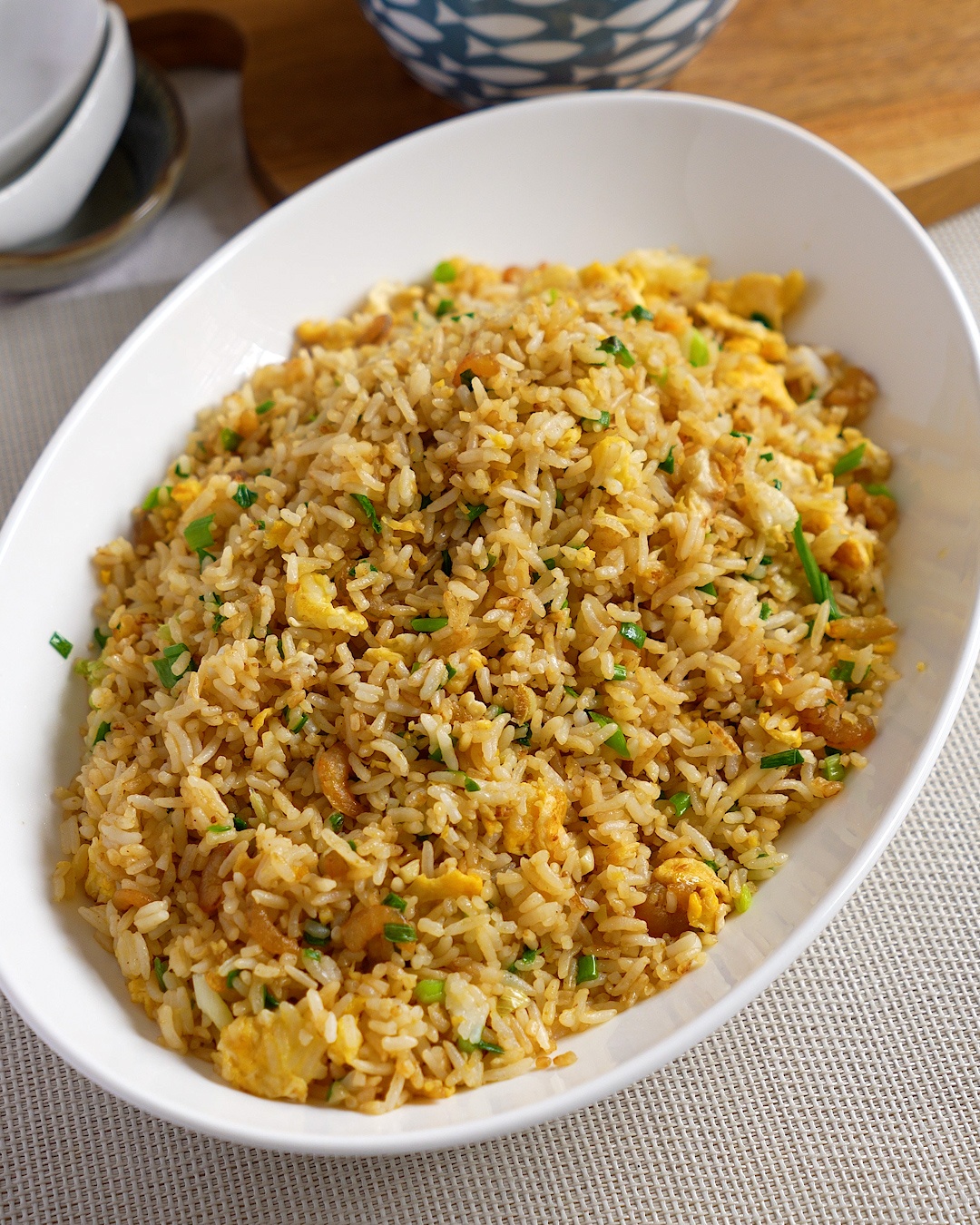 Chinese egg fried rice with dried shrimp, scrambled egg and spring onions in a white serving dish