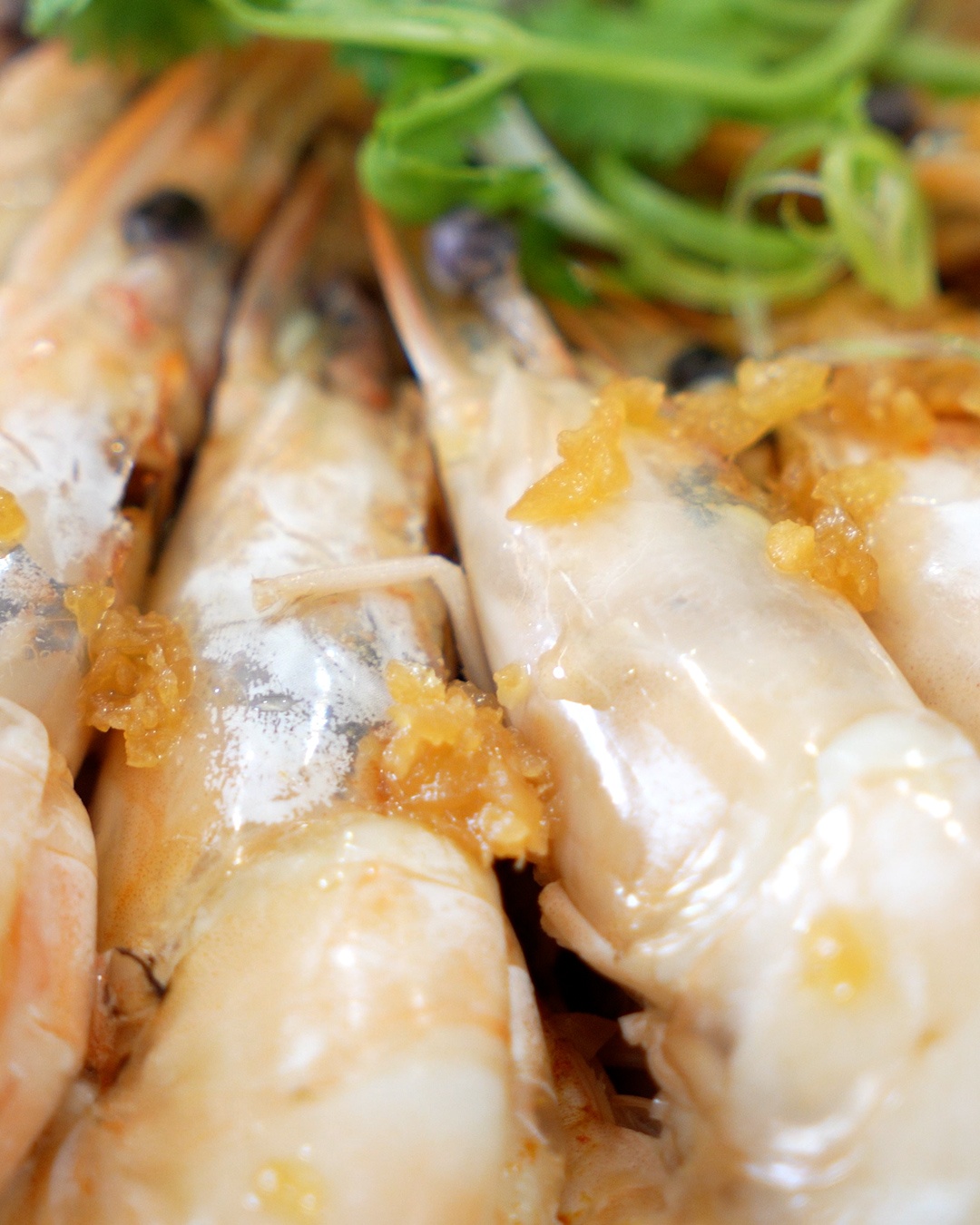 Close-up of shell-on prawns topped with golden garlic and coriander in garlic prawn glass noodles